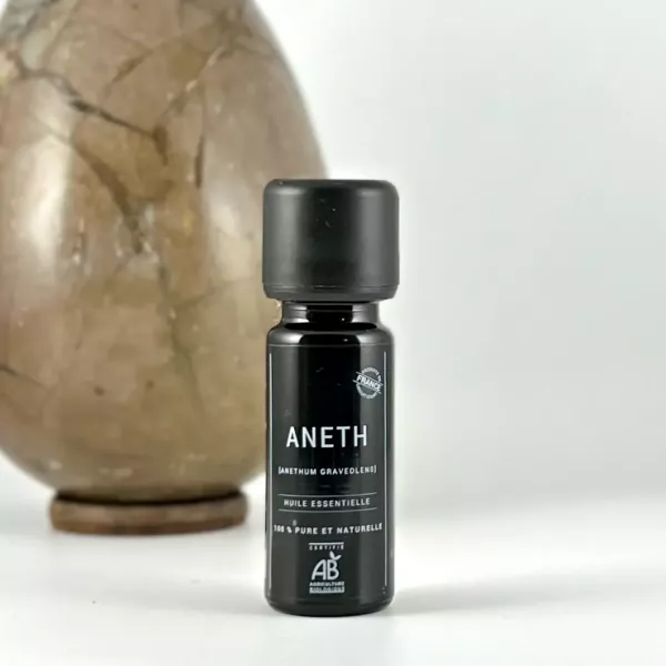 Flacon d’huile essentielle d’aneth BIO Olessen à côté d’un galet