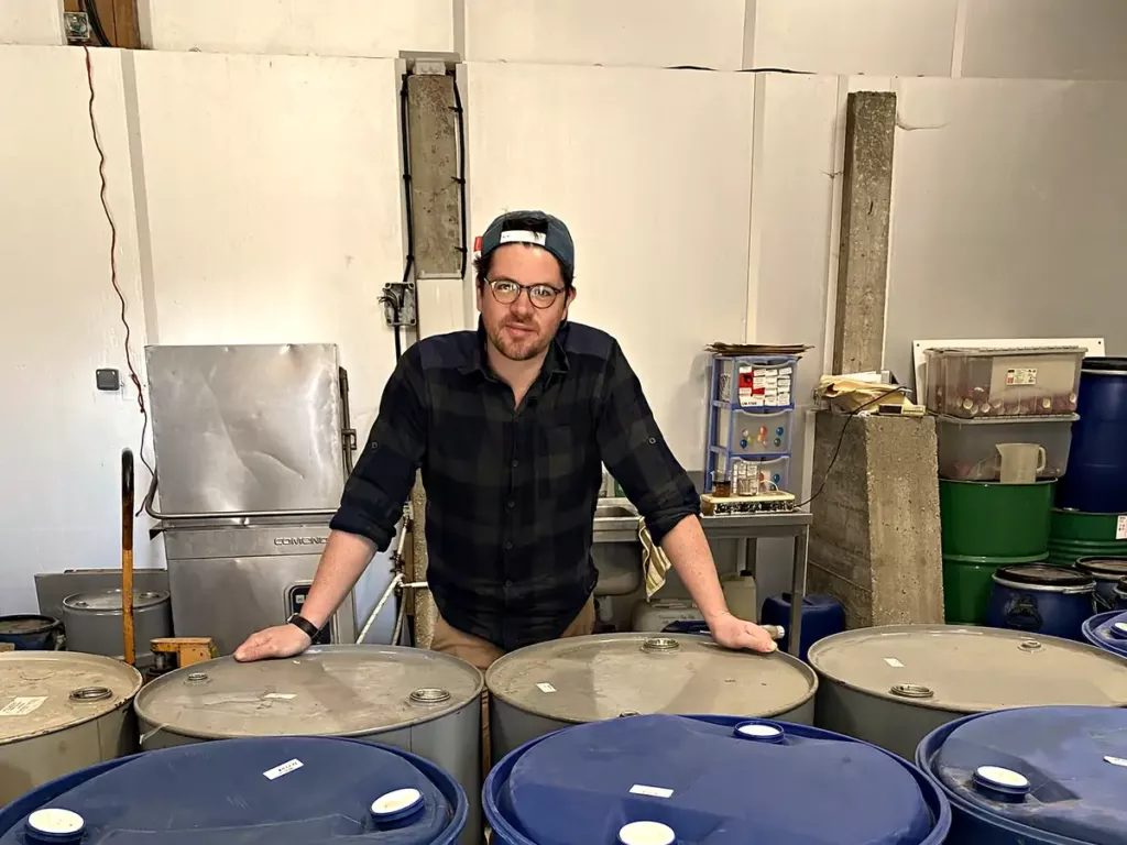 Valentin Raoul, souriant, au milieu des fûts d’huiles essentielles de son chai