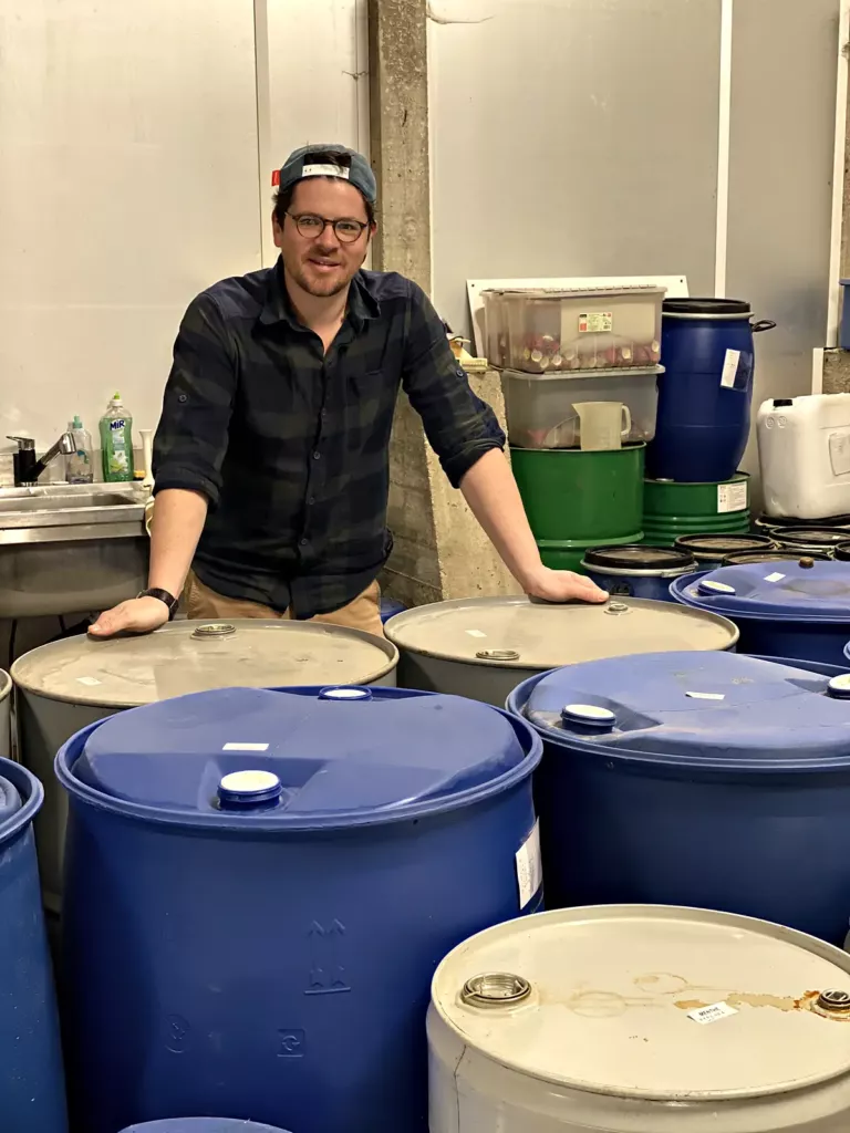 Valentin Raoul, producteur, accoudé aux fûts d’huiles essentielles dans le chai de Foucrainville